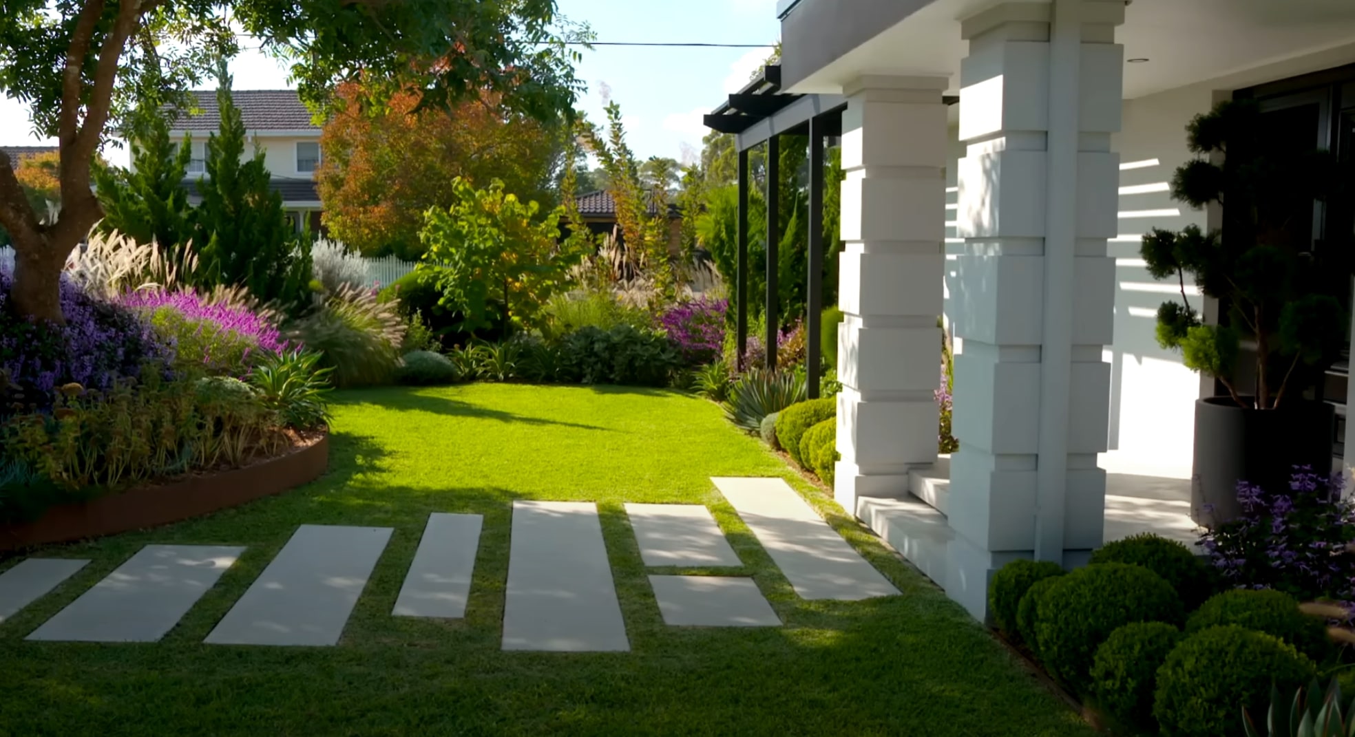 Professional lawn installation with mature landscaping and vibrant plant borders Beautiful landscaped yard with perfect lawn and colorful garden borders